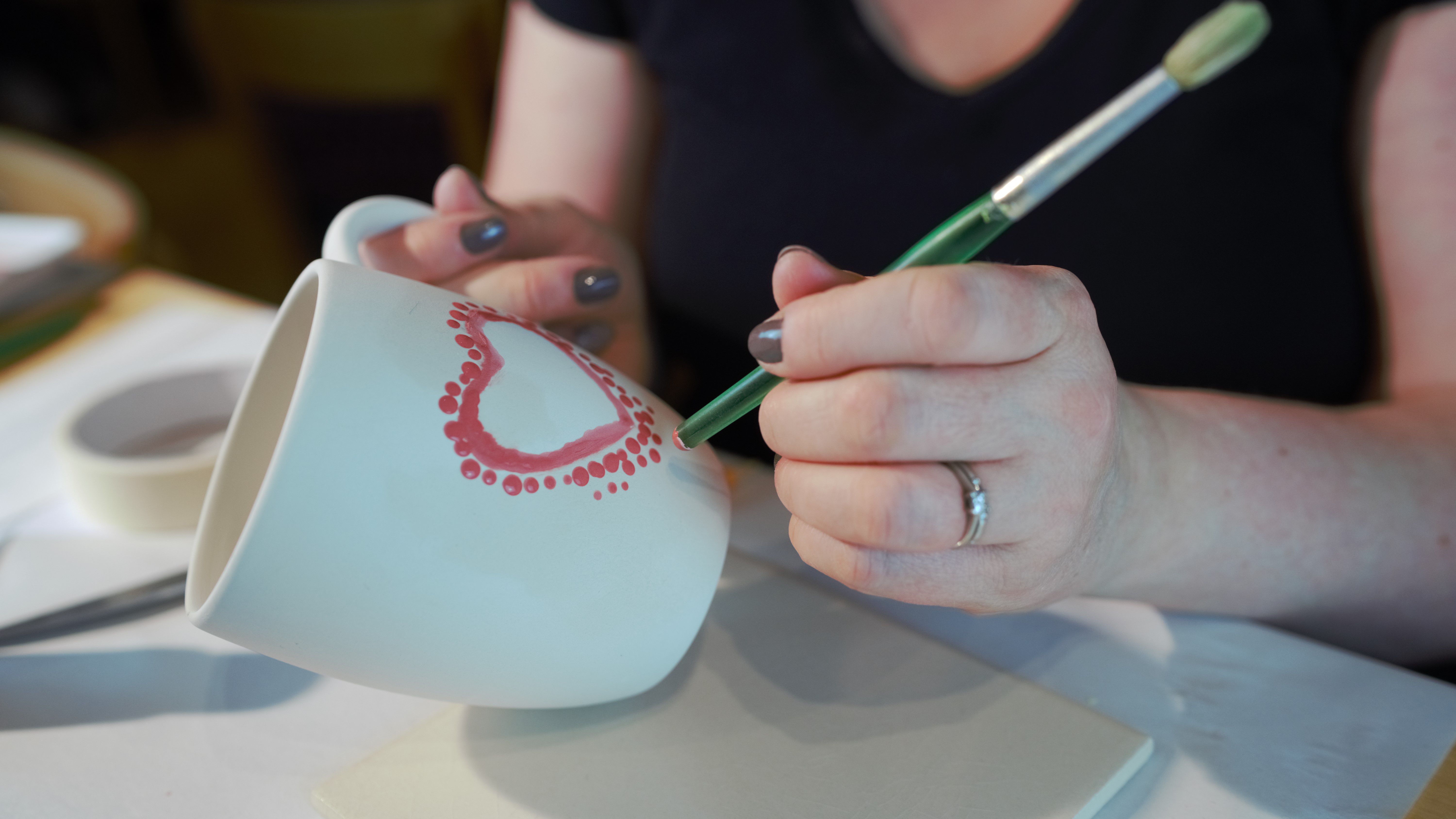 woman-spot-painting-red-heart-on-mug